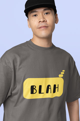 Person wearing a gray t-shirt with a yellow 'BLAH' graphic on a light blue background